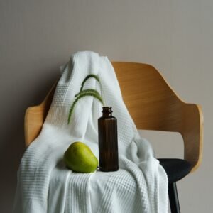 a bottle and a pear on a towel on a chair